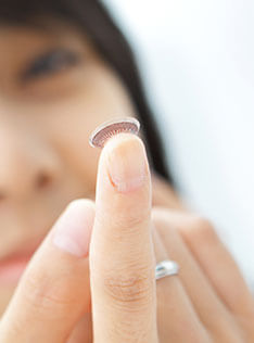 A woman holding out contact lenses on her fingertips
